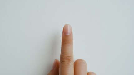 Raised Finger: A single finger is pointing upwards against a simple, clean white backdrop. Focus on communication through simple gestures. 