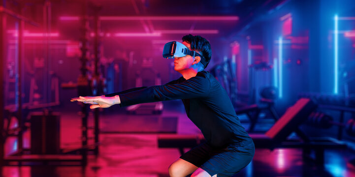 Asian man wearing VR glass while exercising at futuristic gym with glowing vibrant color. Male model using augmented reality technology for analysis data. Technology innovation concept. Ingenuity.