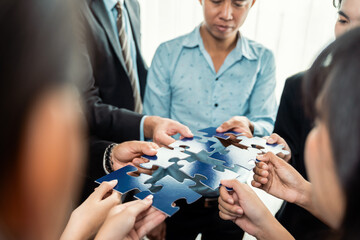 Multiethnic business people holding jigsaw pieces and merge them together as effective solution...