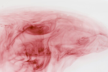 color cloud of red ink in water forming tatters and strips of color