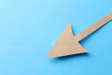 One kraft paper arrow on light blue background, top view. Space for text