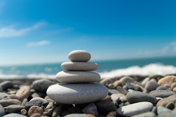 A pyramid of sea pebbles on a sunny pebble beach. The concept of life balance and harmony