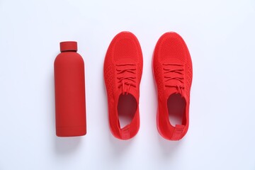 Sneakers and water bottle on white background, flat lay. Sports equipment