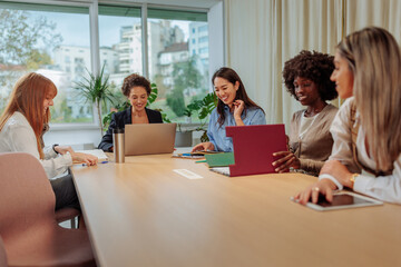 Businesswomen smiling during a meeting inside of the glass office
