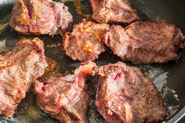 pieces of seasoned beef cheeks sprinkled with flour frying in oil