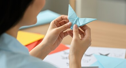 Asian woman holding blue origami butterfly in hands