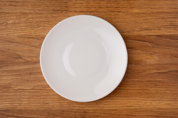 Empty white ceramic plate on wooden table
