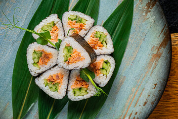 Savoring Delicate Sushi Rolls Arranged Artfully on Green Leaves in an Inviting, Unique Presentation Perfect for Culinary Enthusiasts and Gatherings.