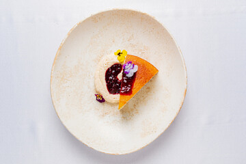 Delicate Dessert Art Featuring a Slice of Vibrant Cake With Colorful Blooms Atop Creamy Base, Presented on a Sleek Plate.