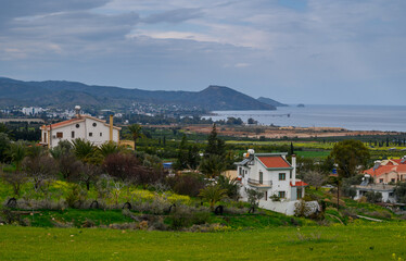 Tranquil coastal village nestled among hills and lush green fields on an overcast day