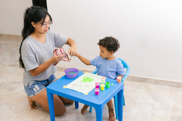 Obraz premium Latin american mother helping her son painting at home