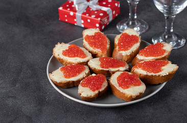 Sandwiches with red caviar on white bread toasts on round plate on Valentines Day