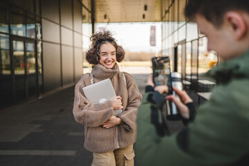 young man take a photo on mobile phone of young woman outdoor