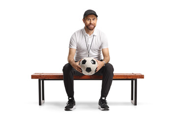 Football coach sitting on a bench and holding a ball