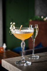 Delightful Cocktail Garnished With Flowers Served in a Chic Bar While a Sparkling Drink Adds Elegance to the Lively Atmosphere During an Evening Gathering.