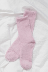 Soft and Cozy Pink Fluffy Socks on White Fabric Background – Warm and Minimalist Flat Lay