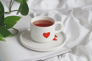Cozy Tea Moment: A White Cup with a Heart Design on Soft White Bedding