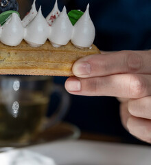 Person holding a pastry with whipped cream on top