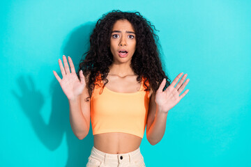 Surprised female gesturing stop against vibrant teal background, showcasing expressive pose with...
