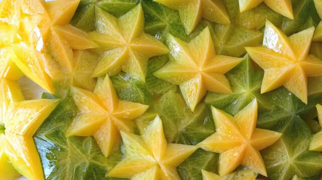 A seamless surface of starfruit slices, their unique star-shaped forms densely covering the entire frame with vibrant green-yellow hues.