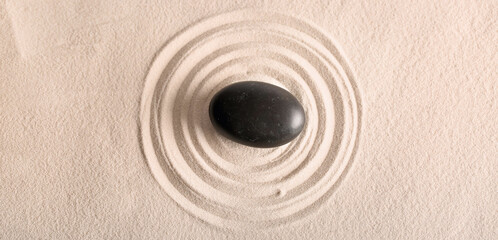 Black stone on light sand with lines. Zen concept