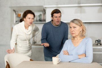 Obraz premium Adult children man and woman clashed over financial question with elderly woman mother. Family feuds, generational conflict, misunderstanding due to different views and opinions