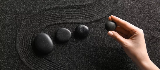 Fotobehang Zen Stenen Female hand and stones on black sand with lines. Zen concept  © Pixel-Shot