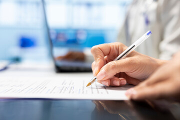 Skilled doctor writing down options and plans for recovery treatment, consulting with his...