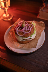 Juicy burger made from draniki and meat patties, lettuce, onion on top and olive. A delicious photo for a menu, culinary website, or an advertisement for catering establishments