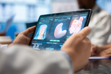 Inside a treatment center, doctor analyze mri brain scan data on a tablet, examining tomography results. Neurology experts team focus on x ray scans and diagnostics for disease prevention. Close up.
