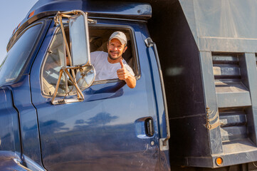 Latino male truck driver gives thumbs up as a sign of having had a good day. Close-up.