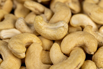large cashew nuts are scattered on a larch board
