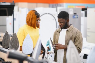 African American couple buying clothes iron in hypermarket
