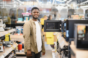 An African-American man is choosing a new microwave oven at an electronics store