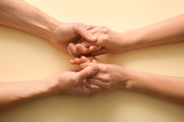 Fototapeta premium Couple holding hands on beige background, top view