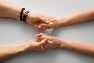 Fototapeta premium Couple holding hands on light background, top view