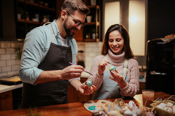 Couple decorating easter eggs in cozy kitchen