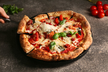 Hand taking slice of tasty pizza Margarita on grunge background