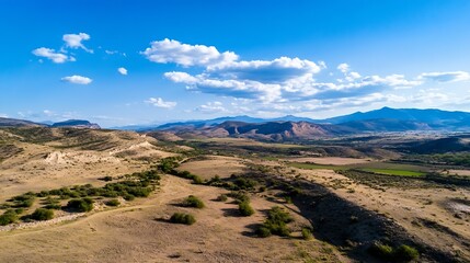 Fototapeta premium Vast Arid Landscape of Rolling Hills and Dramatic Mountains Under a Bright Blue Sky with Fluffy Clouds : Generative AI