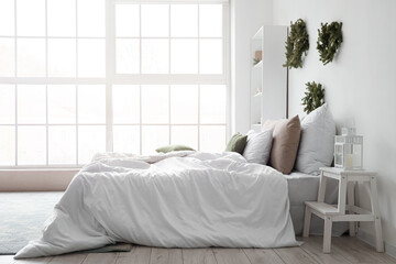 Light interior of bedroom with winter decor and bed