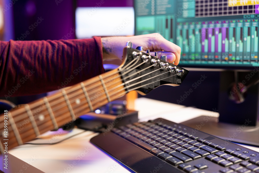 Aufkleber Talented singer tuning his guitar strings for a new audio recording session in his home studio, preparing accords on acoustic instrument to compose a new melody. Artist producing music. Close up.