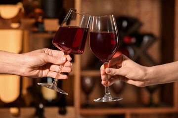 Female hands with glasses of red wine in restaurant