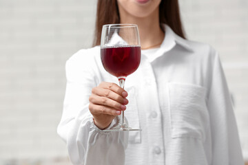 Young woman with glass of red wine on white background, closeup