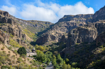 Fototapeta premium Breathtaking landscape featuring a historic Geghard medieval monastery nestled within a rugged mountain valley covered in vibrant green vegetation. Armenia 