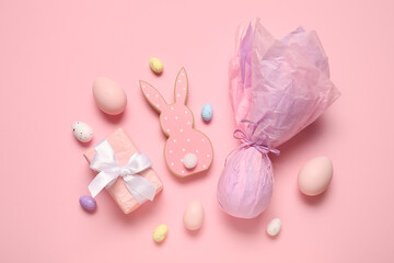 Wooden bunny with Easter eggs and gift box on pink background