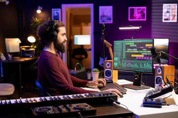 Musical producer working on editing audio recordings with daw software interface on pc, adjusting volume levels for new songs. Artist adding sound effects on tunes, music industry concept.