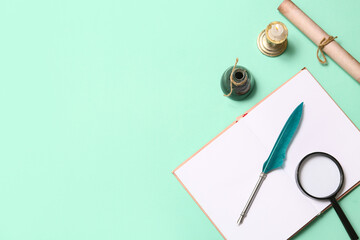 Open book with nib pen, inkwell, scroll and magnifying glass on green background