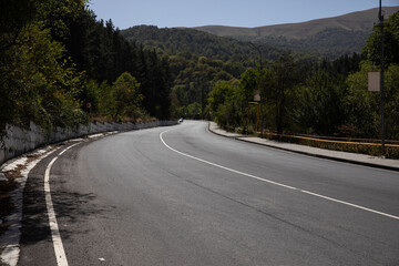 Curving road through a lush mountainous landscape under a clear sky.