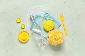 Crumpled plastic bottle with different caps, sponges, microfiber and fork on green grunge background