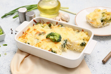 Baking dish with tasty pasta, cheese and broccoli on light background